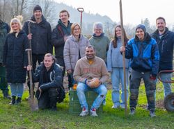KI generiert: Auf dem Bild ist eine Gruppe von Menschen im Freien zu sehen, einige halten landwirtschaftliche Werkzeuge. Sie posieren gemeinsam und scheinen an einer gemeinschaftlichen Garten- oder Landwirtschaftsaktivität teilzunehmen.