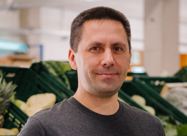 KI generiert: Ein Mann steht vor Kisten mit grünem Gemüse in einem Innenraum.