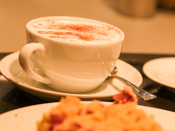 KI generiert: Eine Tasse Cappuccino mit Schaum und Zimt, auf einem Teller serviert.