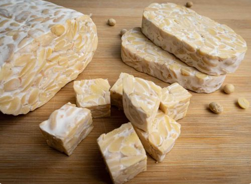 KI generiert: Mehrere Stücke von geschnittenem und gewürfeltem Tempeh auf einem Holzbrett.